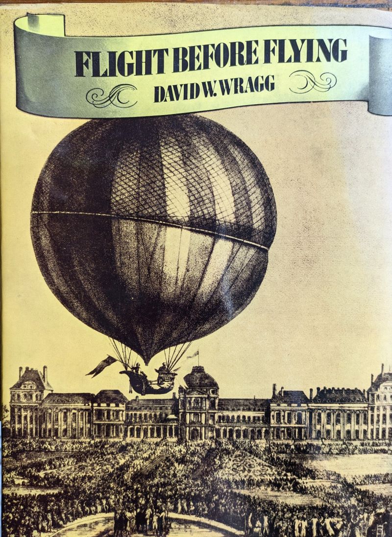 Picture of rear cover of dust jacket showing early 18th century gas balloon with occupants in boat shaped gondola flying low over large crowd standing in the grounds of a large grand building.